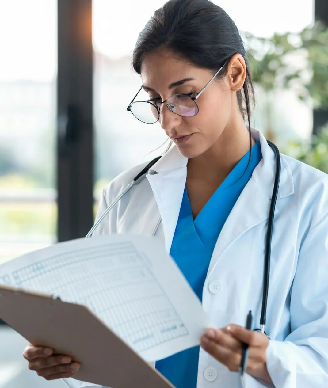 Beautiful female doctor reviewing medical documents while standing in the consultation.