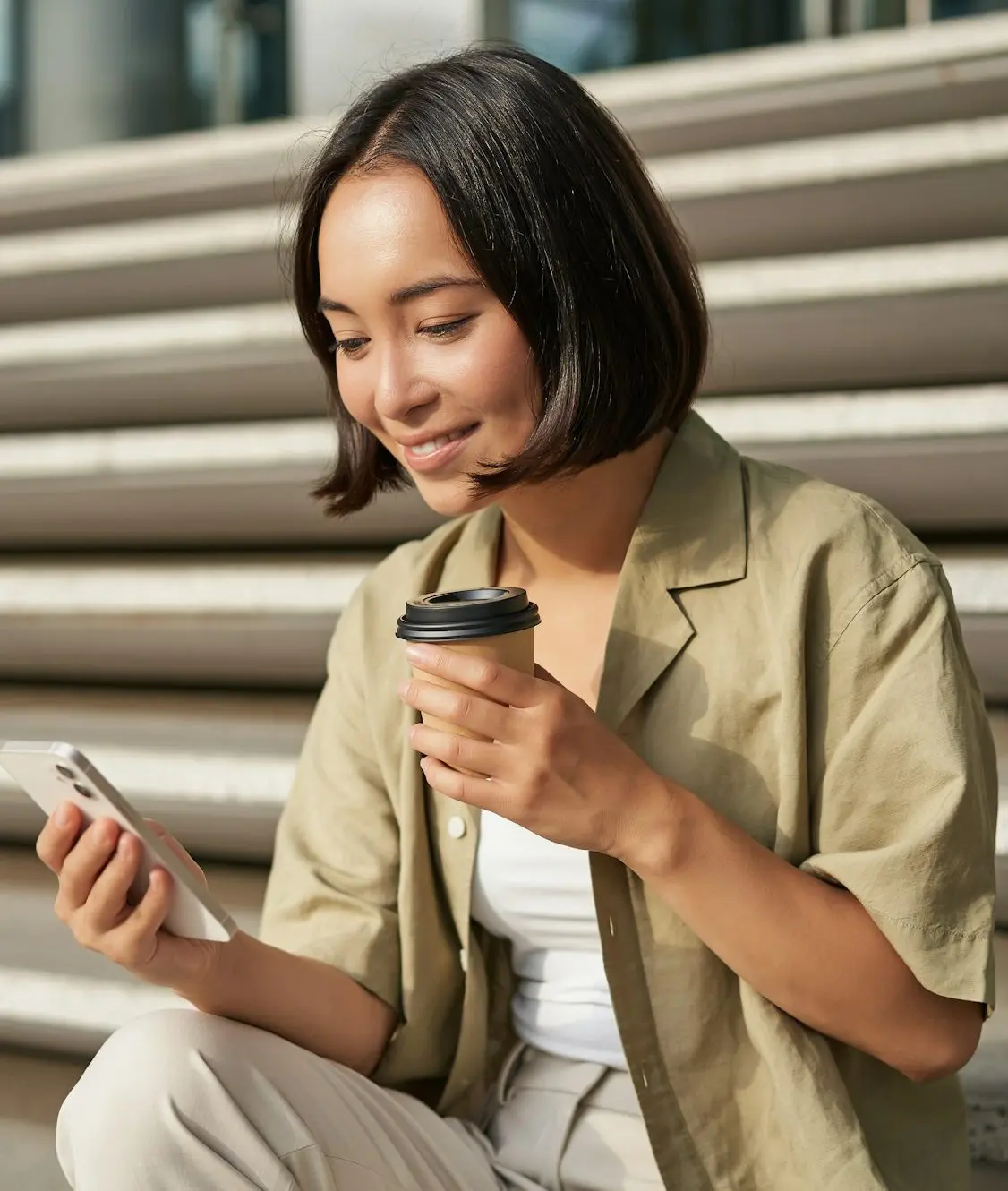 Portrait of asian woman with smartphone, drinks coffee and watches videos on mobile phone. Girl